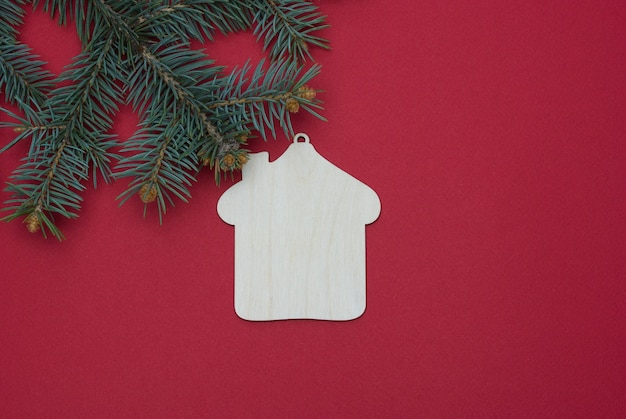 Branche d'arbre de Noël avec des jouets de Noël en bois sur fond rouge