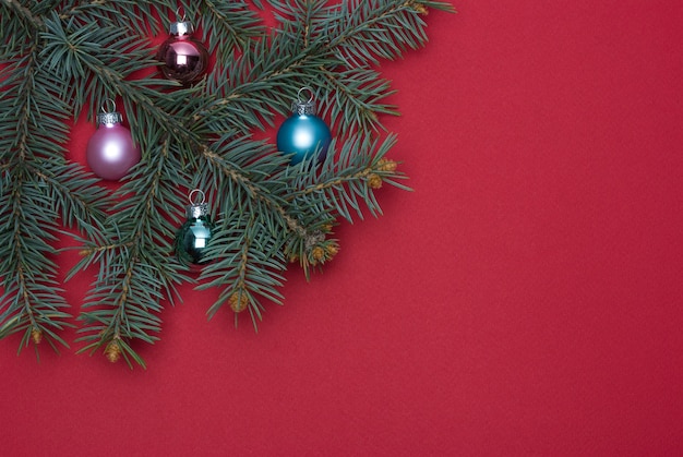 Branche d'arbre de Noël avec des jouets de Noël sur fond rouge.