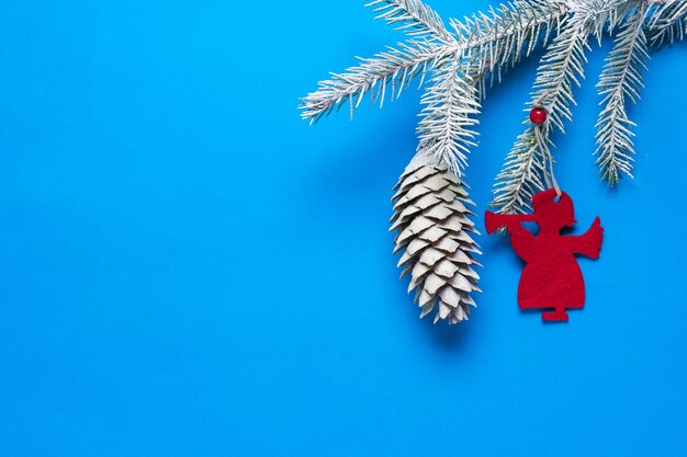 Branche d'épinette avec un cône dans la neige et décoration en forme d'ange. Préparer Noël