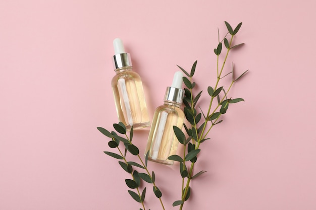 Branche d'eucalyptus et bouteilles d'huile sur fond rose