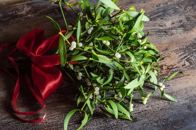 Branche de gui de Noël avec arc rouge sur la table en bois