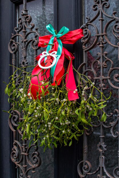 Une branche de gui verte ornée d'un nœud rouge sur les portes d'entrée
