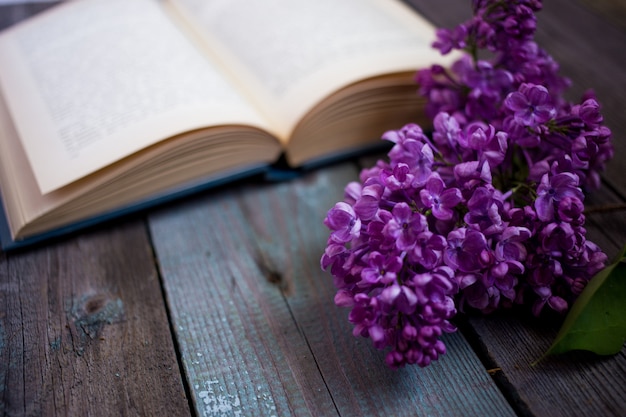 Branche de lilas et livre ouvert sur un fond en bois