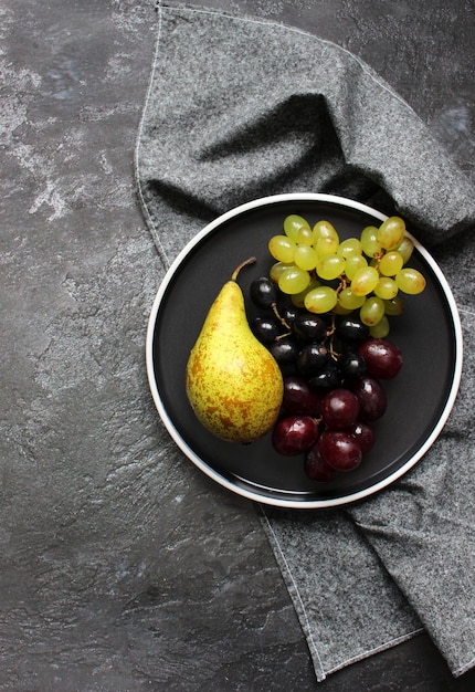 Branche de raisin vert mûr sur une assiette avec des gouttes d'eau Raisins juteux sur fond de bois agrandi Raisins sur une table de cuisine sombre avec espace de copie