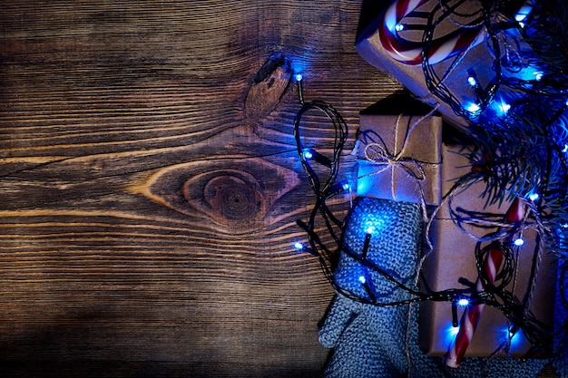 Branche de sapin avec des lumières de Noël bleues, une boîte-cadeau et des cannes de bonbon sur fond en bois avec espace de copie. Vue de dessus. Nature morte.