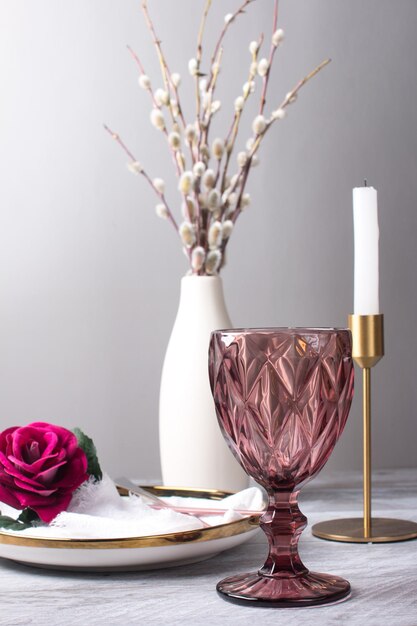 Une branche de saule moelleuse dans un vase sur la table Un verre de vin rose et une bougie blanche Célébration du Dimanche des Rameaux