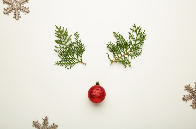 Branche de thuya et décoration de boule rouge de Noël sur fond blanc. Vue de dessus.