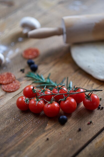 Photo branche de tomates cerises allongé sur la table. différents ingrédients flous