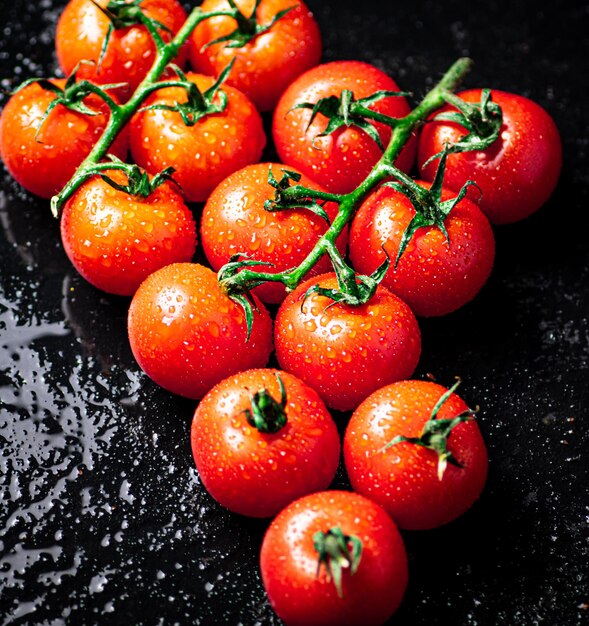 Une branche de tomates mûres sur une table humide