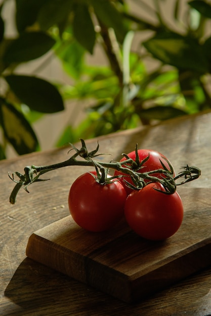 Une branche de tomates rouges se trouve sur une planche de bois