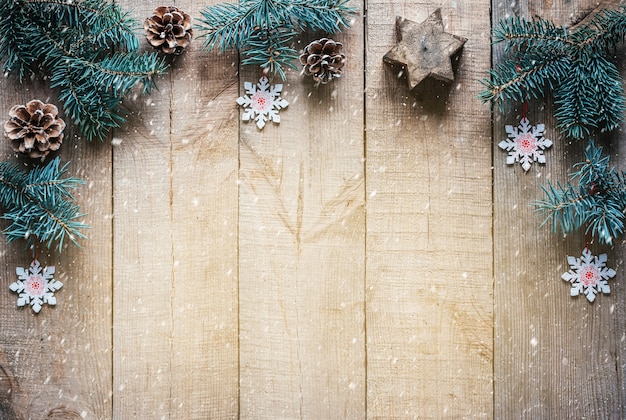 Branches d'arbre de Noël pommes de pin snoflakes et étoile de bougie sur fond de bois