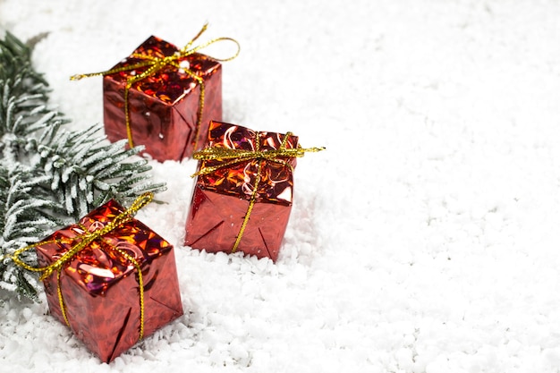 Branches d'un arbre de Noël et trois cadeaux dans une boîte rouge dans la neige