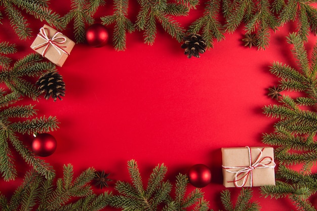 Branches d'arbres de Noël, cadeaux et pommes de pin sur un fond rouge, Noël, carte de voeux.