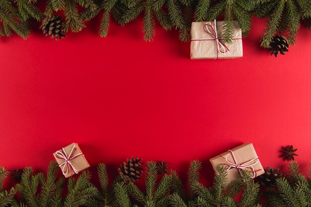 Branches d'arbres de Noël, cadeaux et pommes de pin sur un fond rouge, Noël, carte de voeux.