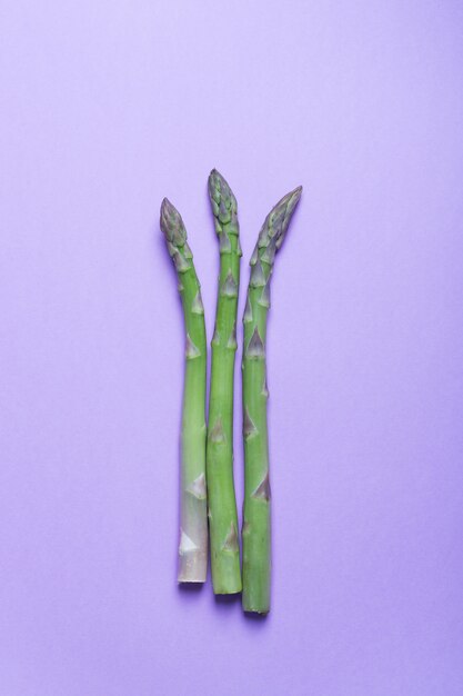 Branches d'asperges vertes fraîches sur la surface lilas