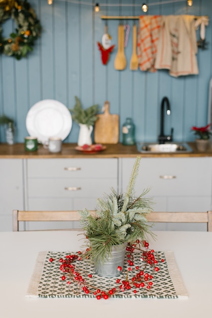 Branches d'épicéa dans un seau décoratif en métal sur la cuisine