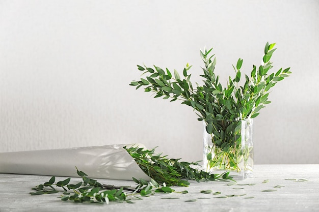 Branches d'eucalyptus vert dans un vase et papier d'emballage sur table