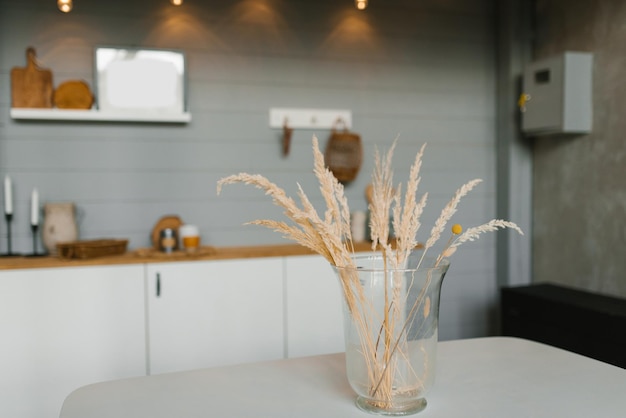 Branches d'herbe sèche dans un vase en verre sur la table de la cuisine scandinave