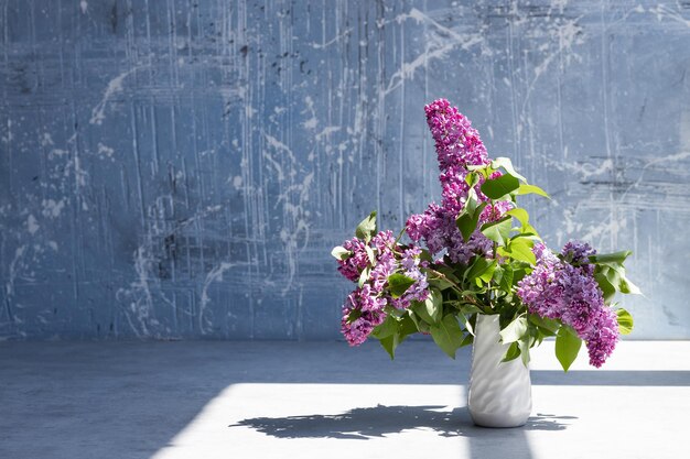 Branches de lilas violet frais dans un vase blanc