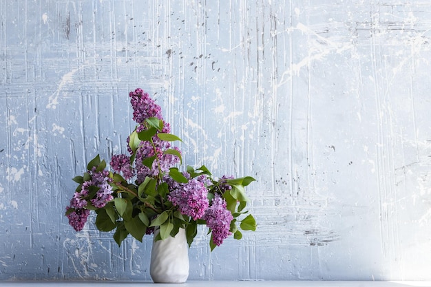 Branches de lilas violet frais dans un vase blanc