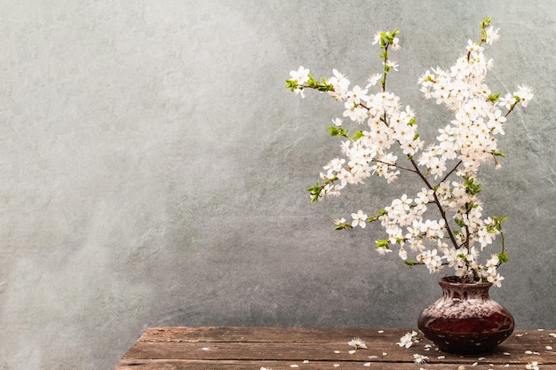 Branches de prune cerise en fleurs dans un vase Carte de voeux festive style rustique vintage Fond de pierre