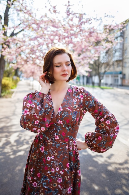 Branches de Sakura avec des fleurs sur un arbre dans les rues de la ville. Fille de femme heureuse filature dans la rue avec sakura en fleurs. Sakura fleurit.