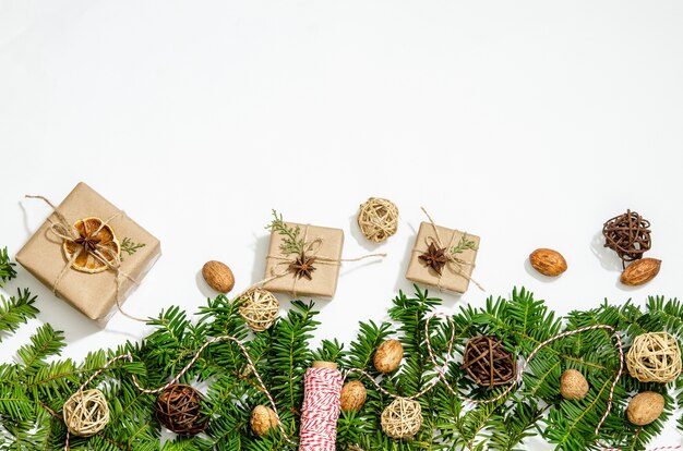 Branches de sapin, coffrets cadeaux, anis étoilé, tranches d'orange sèches, boules décoratives et noix sur fond blanc. Copiez l'espace, pose à plat.