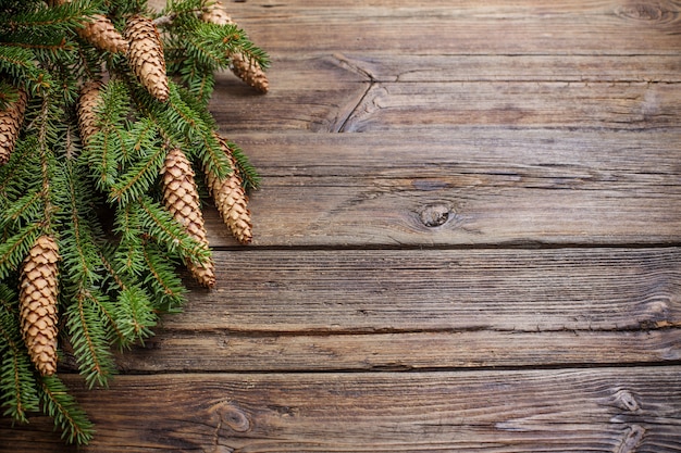 Branches de sapin avec des cônes sur fond de bois brun