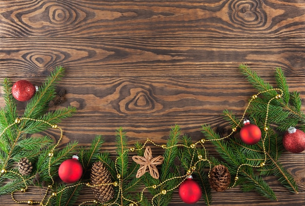 Branches de sapin décorées de cônes de boules de Noël et d'une étoile sur fond de bois