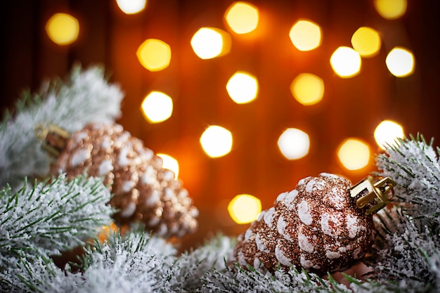 branches de sapin enneigées sur fond de guirlandes de lumières floues sur une fontaine en bois