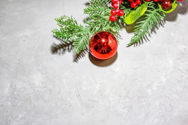 Branches de sapin de Noël avec des baies de sorbier rouge boule rouge sur fond gris Vue de dessus à plat