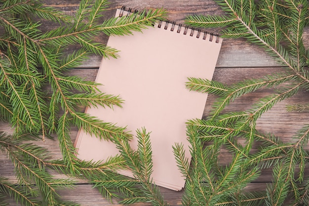 Branches de sapin de Noël sur planche de bois avec cahier vierge.