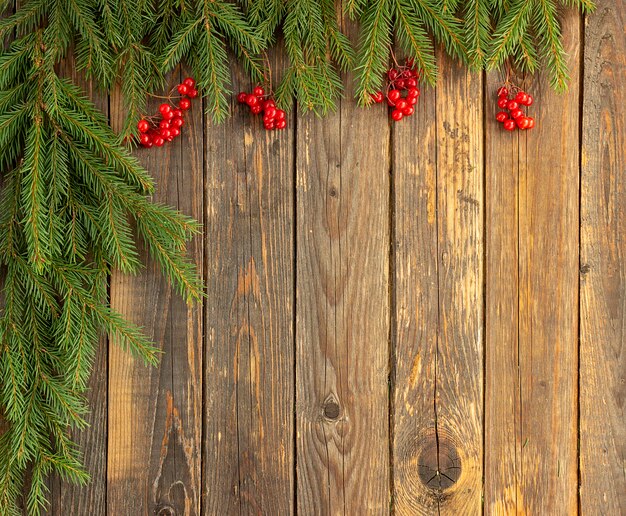 Branches de sapin vert et baies rouges sur fond de bois. Concept de Noël et du nouvel an. Place pour votre texte.