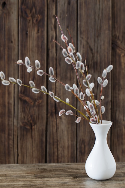 Branches de saule fleuri dans un vase sur fond de bois