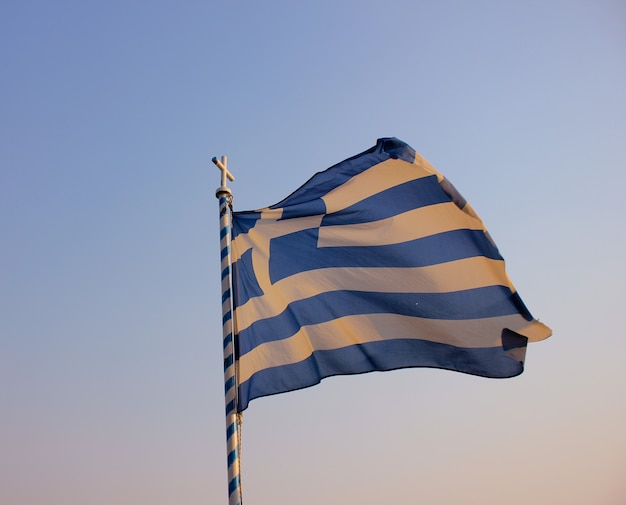 De brandir le drapeau grec contre le ciel bleu