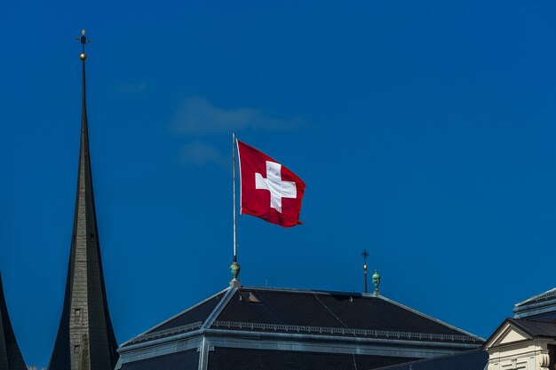 Brandir le drapeau suisse dans le vent contre un ciel bleu