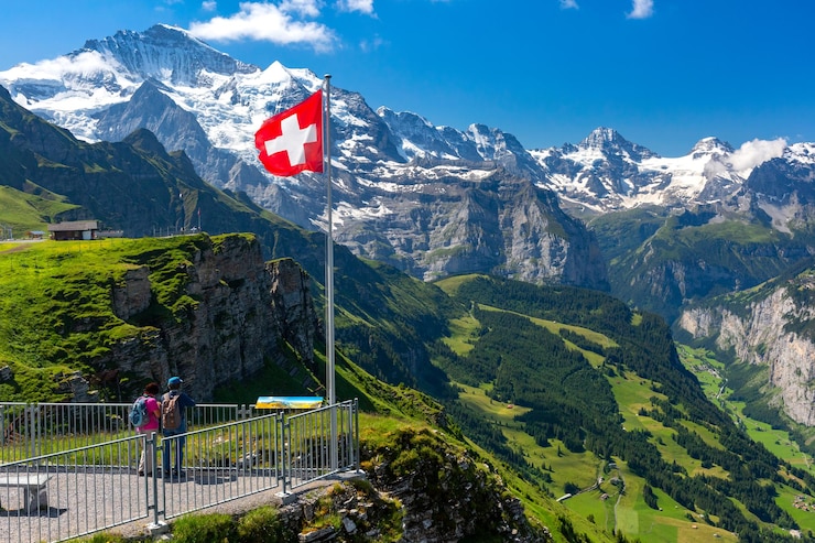 Photo brandir le drapeau suisse et les touristes admirent le sommet de la montagne jungfrau sur le point de vue de mannlichen, oberland bernois suisse