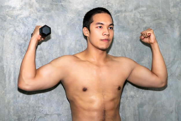 Bras d'entraînement solide homme athlétique bodybuilder asiatique parfait avec haltère sur fond.