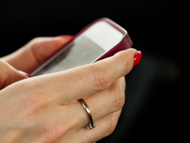 Bras de femme d'affaires tenir et utiliser le téléphone portable closeup