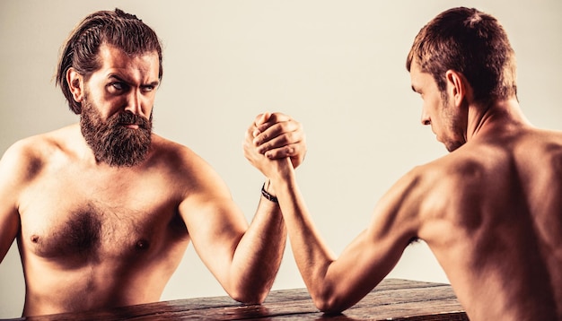 Bras de fer fin main, gros bras fort en studio. Les mains de deux hommes se sont jointes au bras de fer, match fort et faible, inégal.