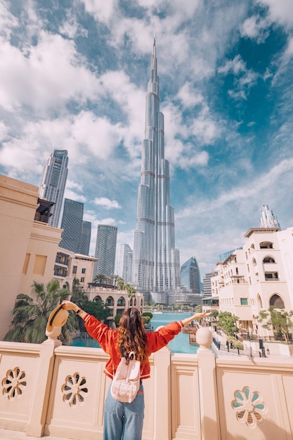 Les bras d'une fille heureuse sont tendus alors qu'elle embrasse la vue incroyable devant elle avec la tour Burj Khalifa irréelle à Dubaï, UAE