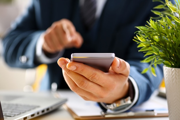 Bras masculin en costume tenir le téléphone