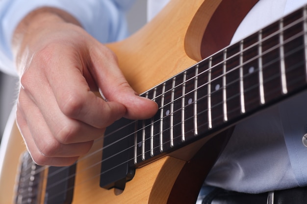 Bras masculins jouant de la guitare électrique de forme classique