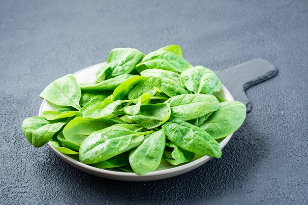 Une brassée de jeunes pousses d'épinards frais dans des gouttes d'eau sur une assiette sur une ardoise. Cuisine végétarienne, bien-être et détox