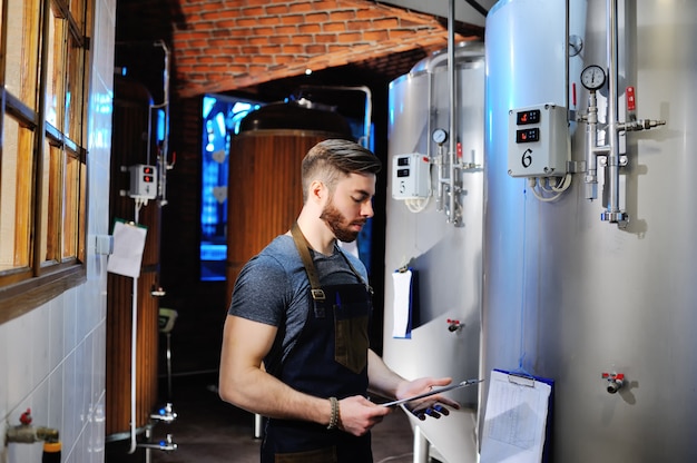 Le brasseur sur le fond des réservoirs de bière fait des calculs