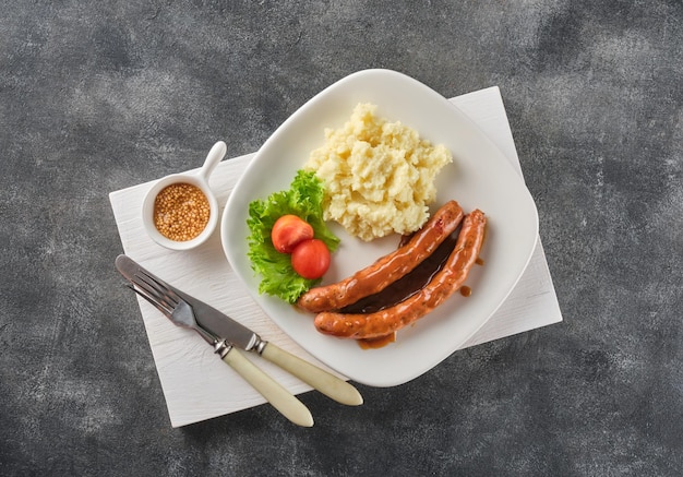 Bratwurst de boeuf grillé avec purée de pommes de terre sur plaque blanche sur fond gris saucisses de boeuf BBQ