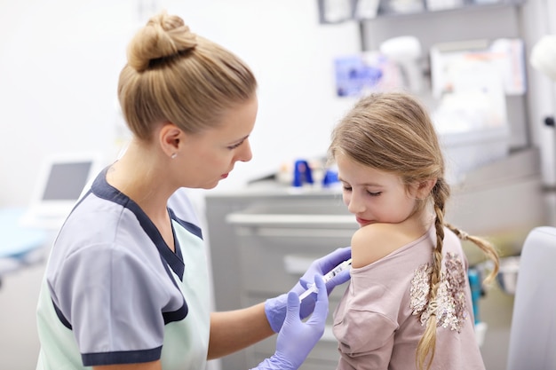 brave petite fille recevant une injection ou un vaccin avec un sourire