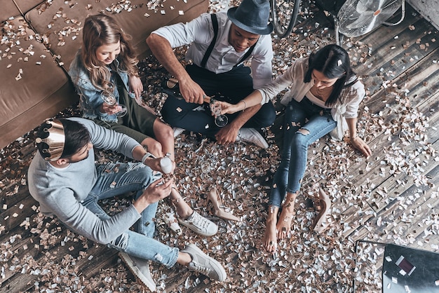 Bravo à l'amitié. Vue de dessus des jeunes modernes versant du champagne