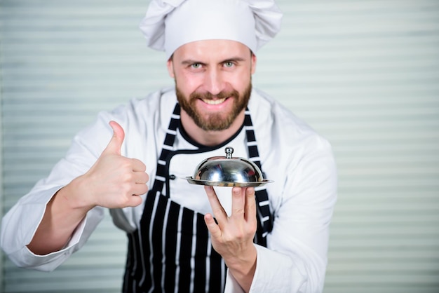 Bravo pour le meilleur menu Bel homme en tablier et chapeau de cuisinier Maître chef servant un repas au restaurant Chef cuisinier en uniforme debout avec un délicieux plat Restaurant décontracté proposant un menu fixe