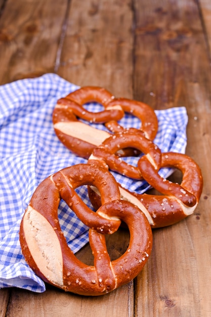 Bretzel bavarois décoré d'un drap bleu et blanc sur une planche de bois rustique